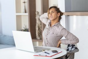 Back Pain After Sitting Too Long affecting an office worker with lower back pain while sitting at a desk